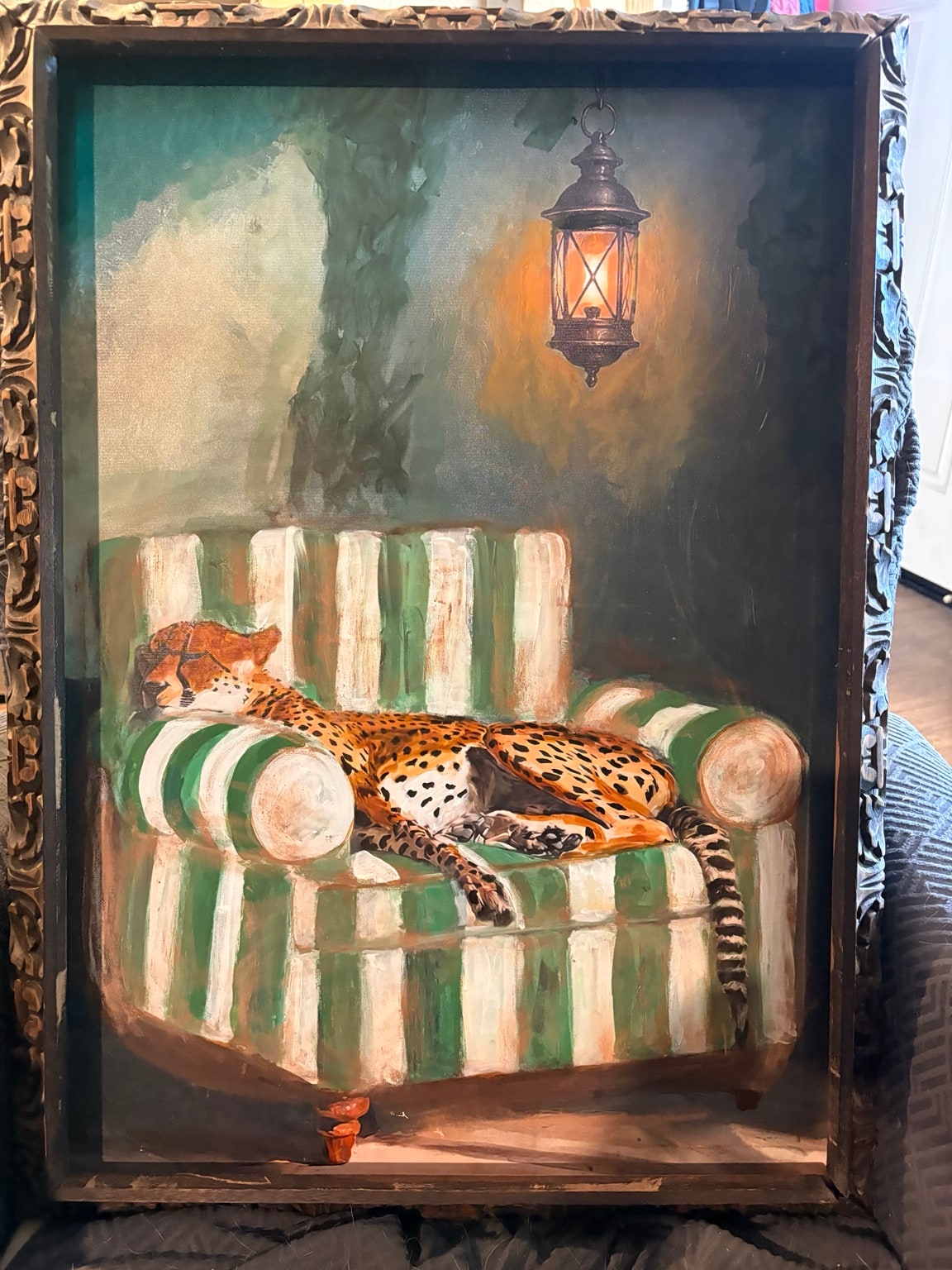 Couch Potato: a cheetah reclining on a green and cream striped couch beneath a lantern